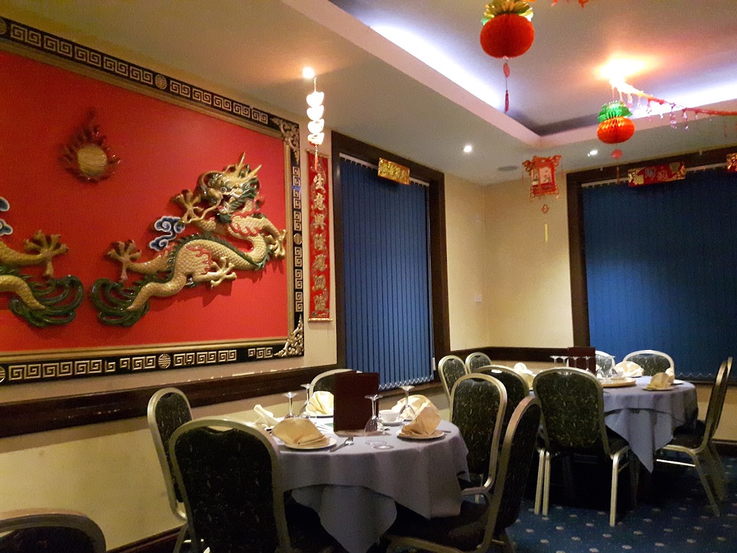Dining room with blue tablecloths and a large red traditional wall hanging